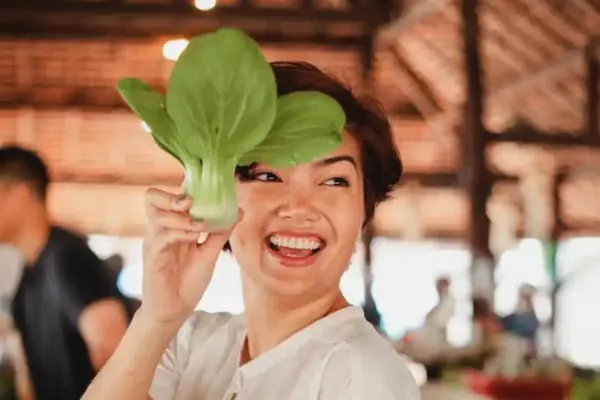 A woman holding a leafy green vegetable