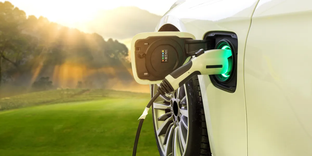 A modern EV charging station installed in a clean, organized garage, charging a sleek electric vehicle.