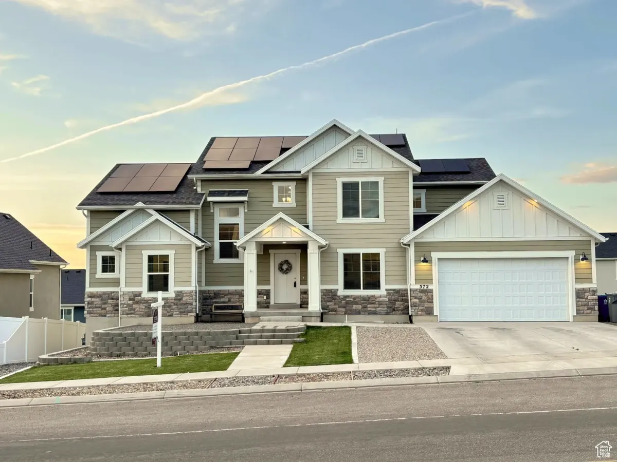 Modern two-story home with solar panels in Elk Ridge, Utah, showcasing sustainable energy under a partly cloudy sky.
