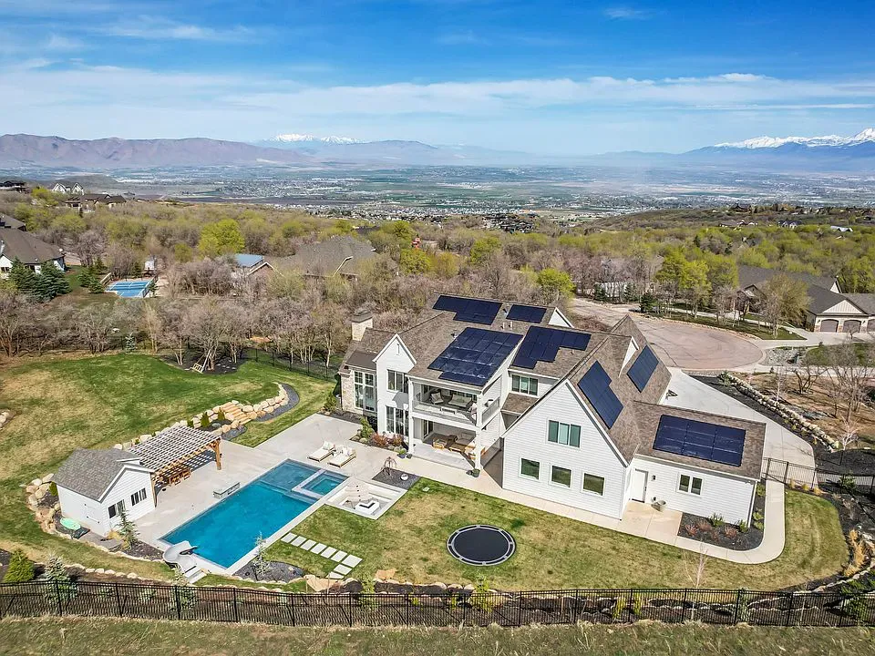 A rustic Woodland Hills, UT home with solar panels glowing under a clear dawn sky, nestled among trees, symbolizing reliable off-grid power.