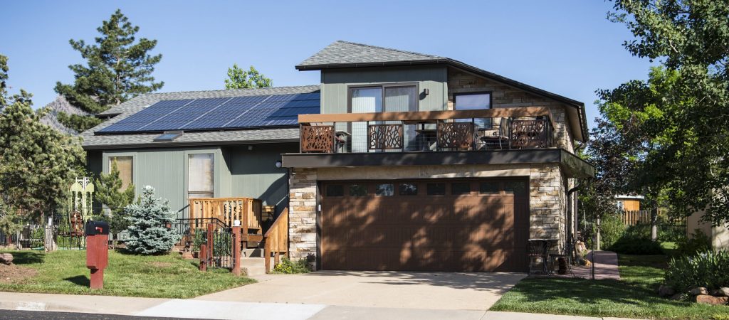 Cedar Hills Utah home with solar panels and Tesla Powerwall against hills, depicting 30% instant rebates for energy stability.