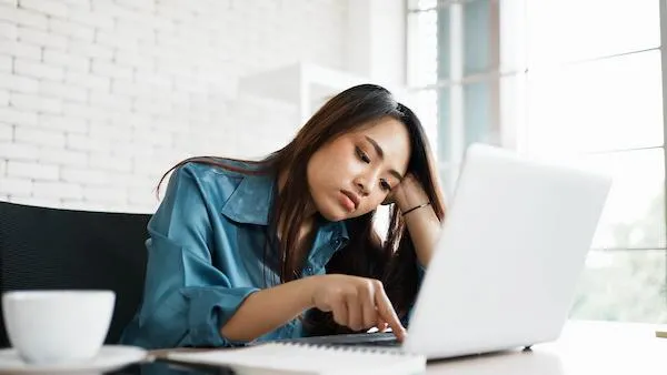 Portrait of bored young asian woman typing laptop in office. 