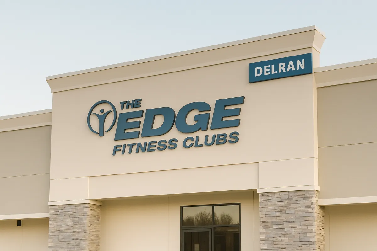 Minimalist exterior photo of The Edge Fitness Clubs in Delran with clean beige architecture, dark blue signage, and soft natural lighting.