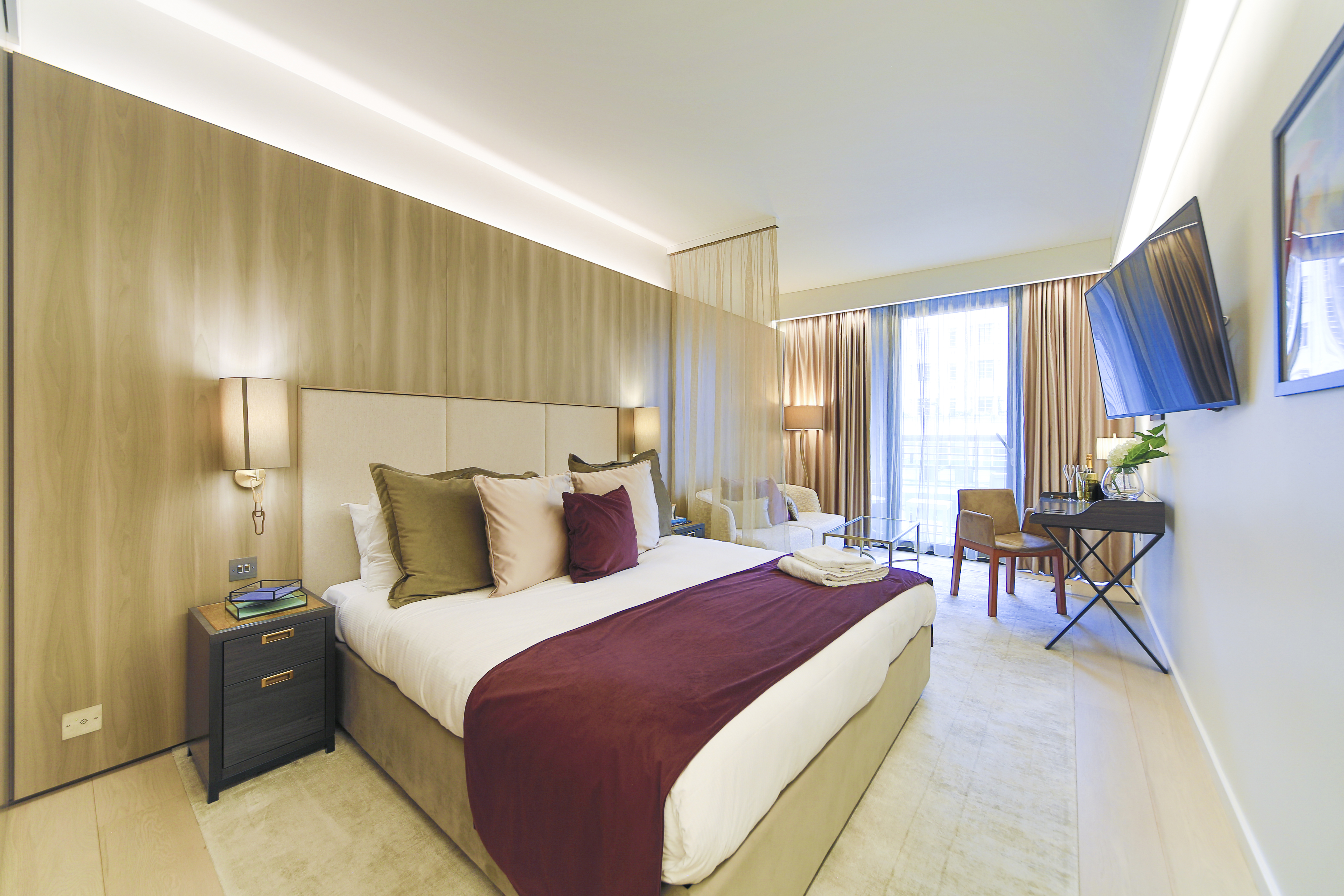 Modern hotel bedroom with desk, seating area and natural light