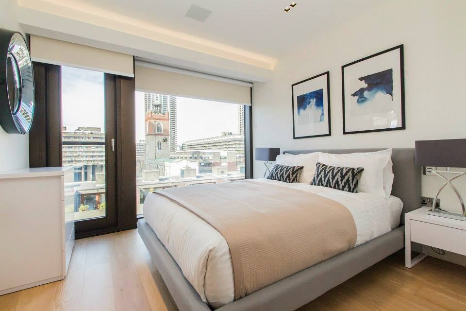 Modern hotel bedroom with king-size bed and large windows overlooking the city in London