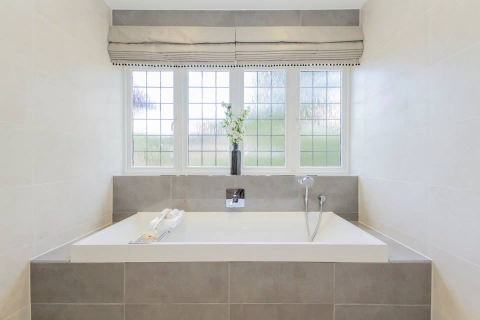 Modern hotel bathroom with built-in bath and neutral tiled interior