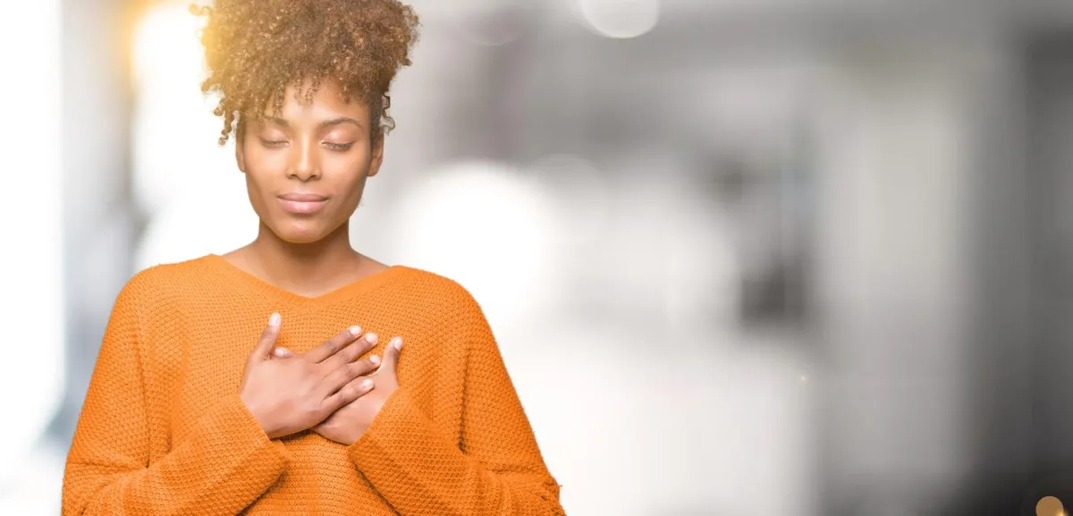 Beautiful young african american woman over isolated background smiling with hands on chest with closed eyes and grateful gesture on face