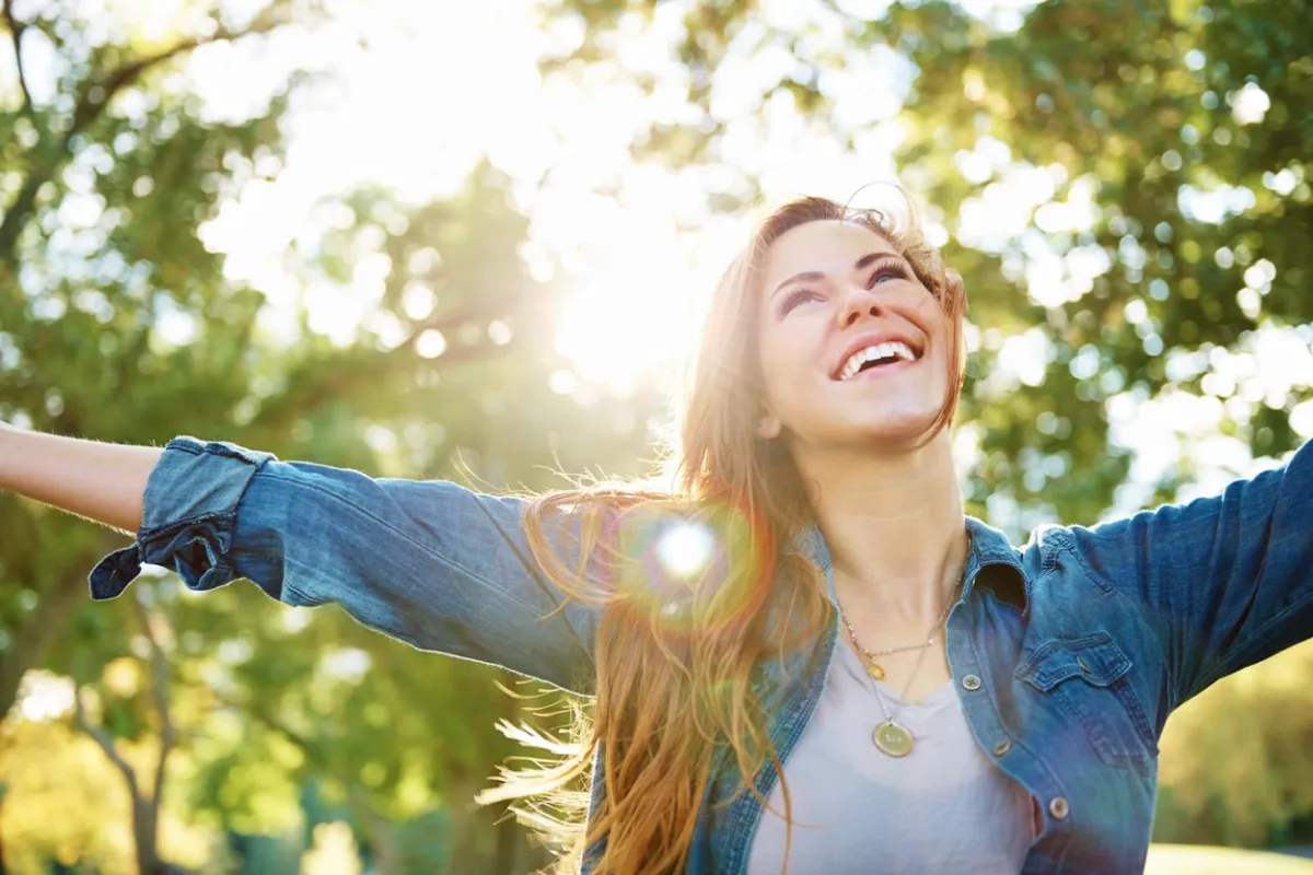 Woman outside with arms outstretched and happy smile on her face.
