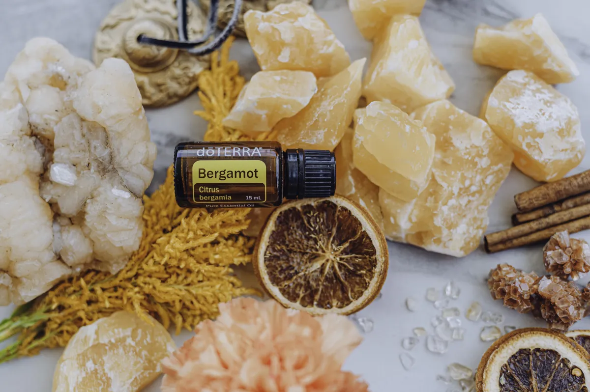 a bottle of Bergamot laying with a selection of crystals, dried orange slices and flowers