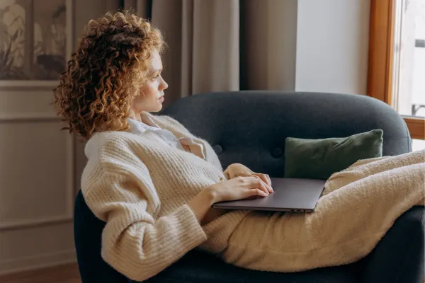 lady sat on a comfy chair with a laptop on her lap