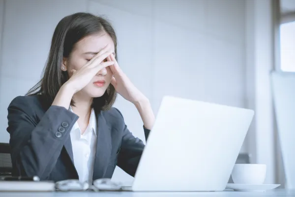 lady sat at laptop with hands over her face