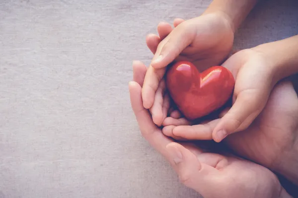 mums hands under a child's hands with a heart in it