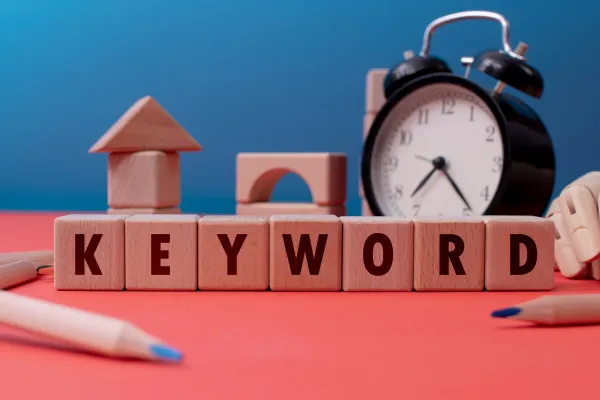 an alarm clock and the words keyword research written on small wooden block