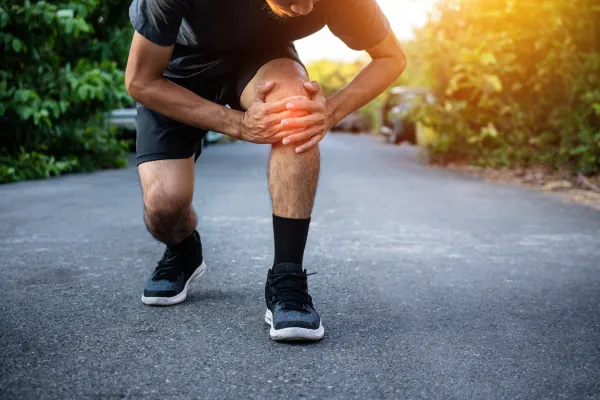 man suffering from knee pain while exercising