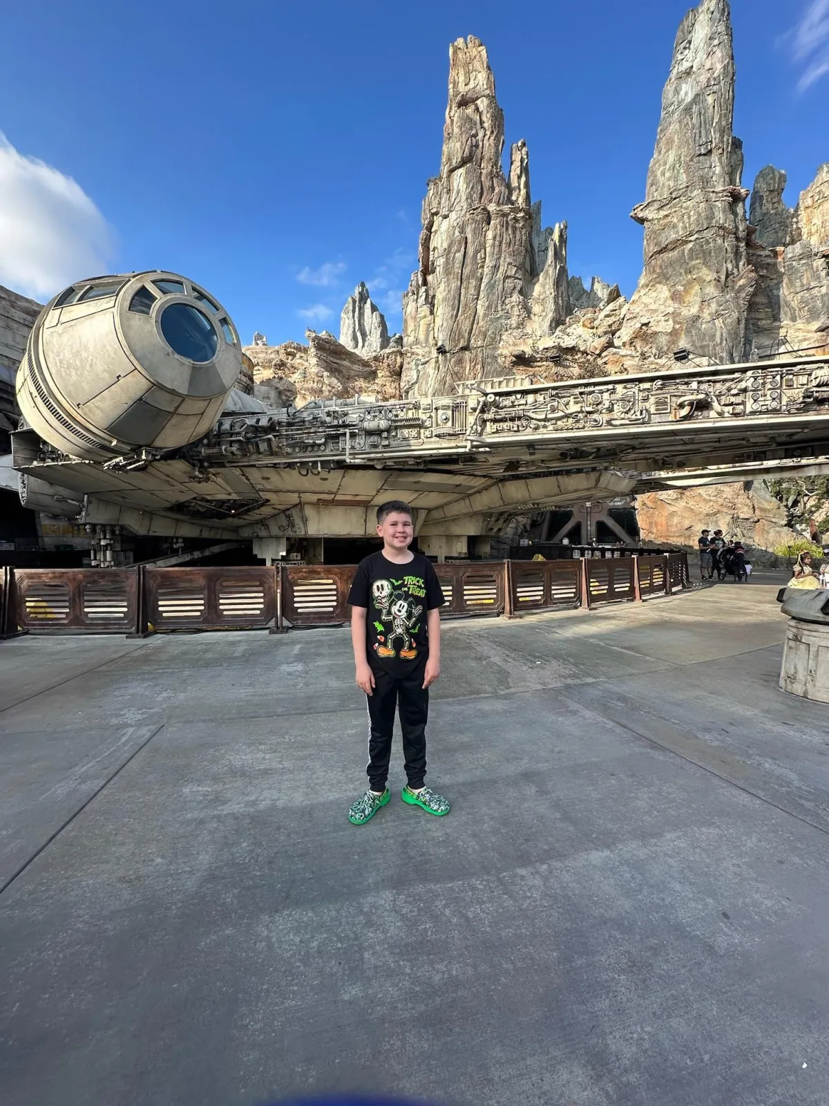 pre-teem boy standing in front of the Millennium Falcon in Galaxy's Edge at Disneyland 