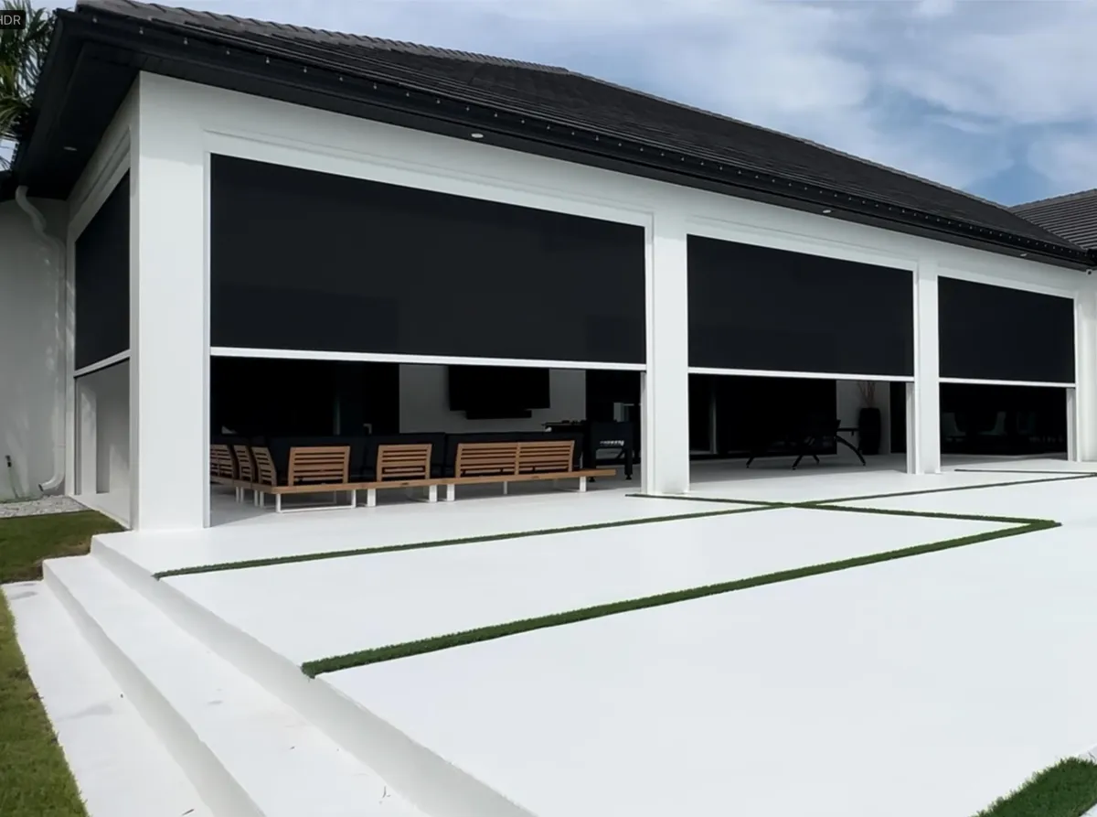 A large white house featuring elegant black MagnaTrack Motorizeed Screens, set against a clear blue sky.