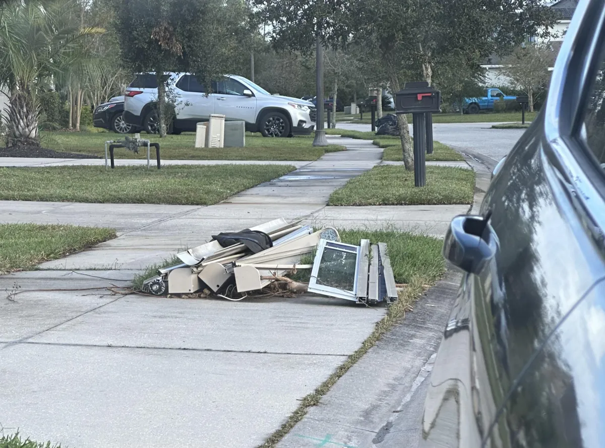 A photo of three torn apart motorized screens damage in the hurricane sitting by the curb waiting for the Garbage Truck.
