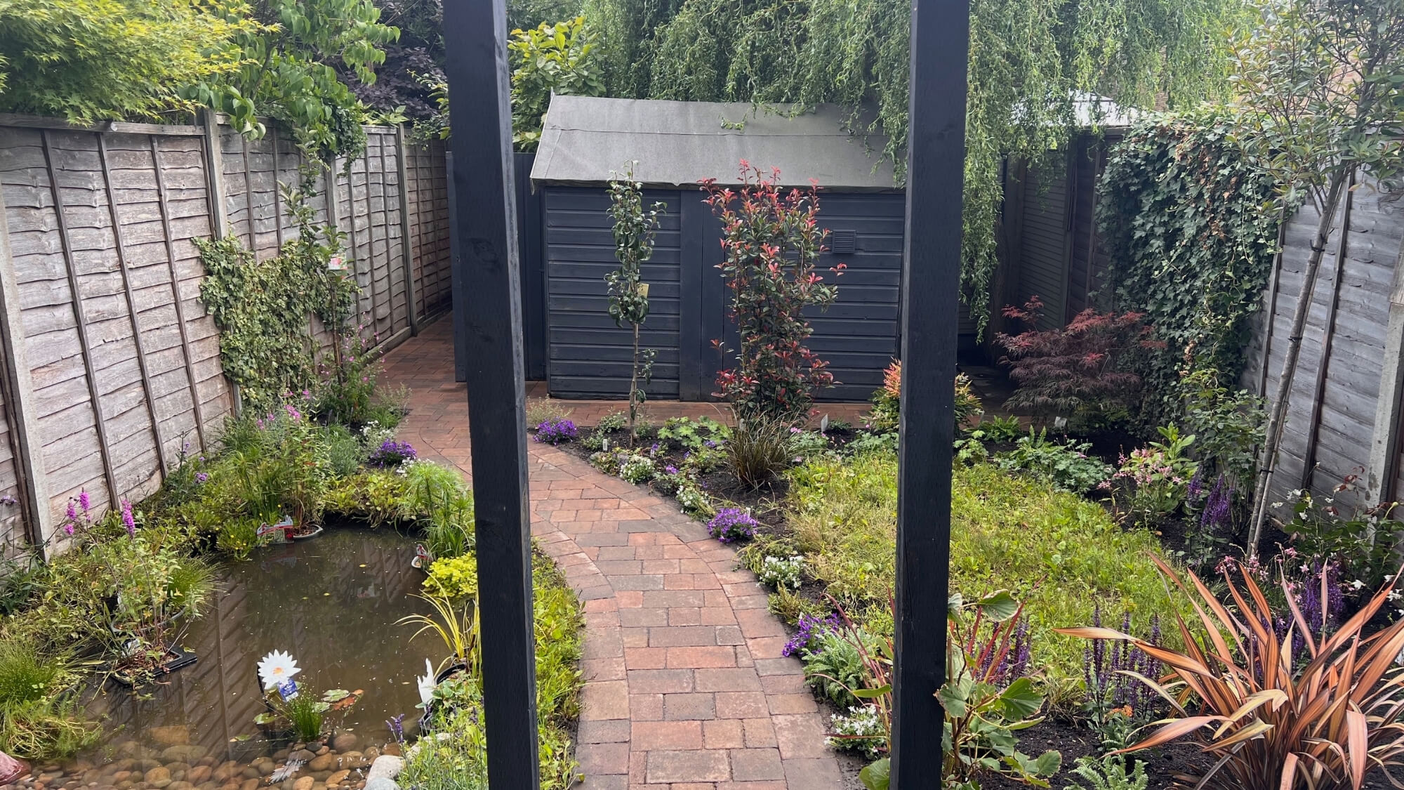 Wildlife-friendly garden with curved pathway and natural-style pond after redesign