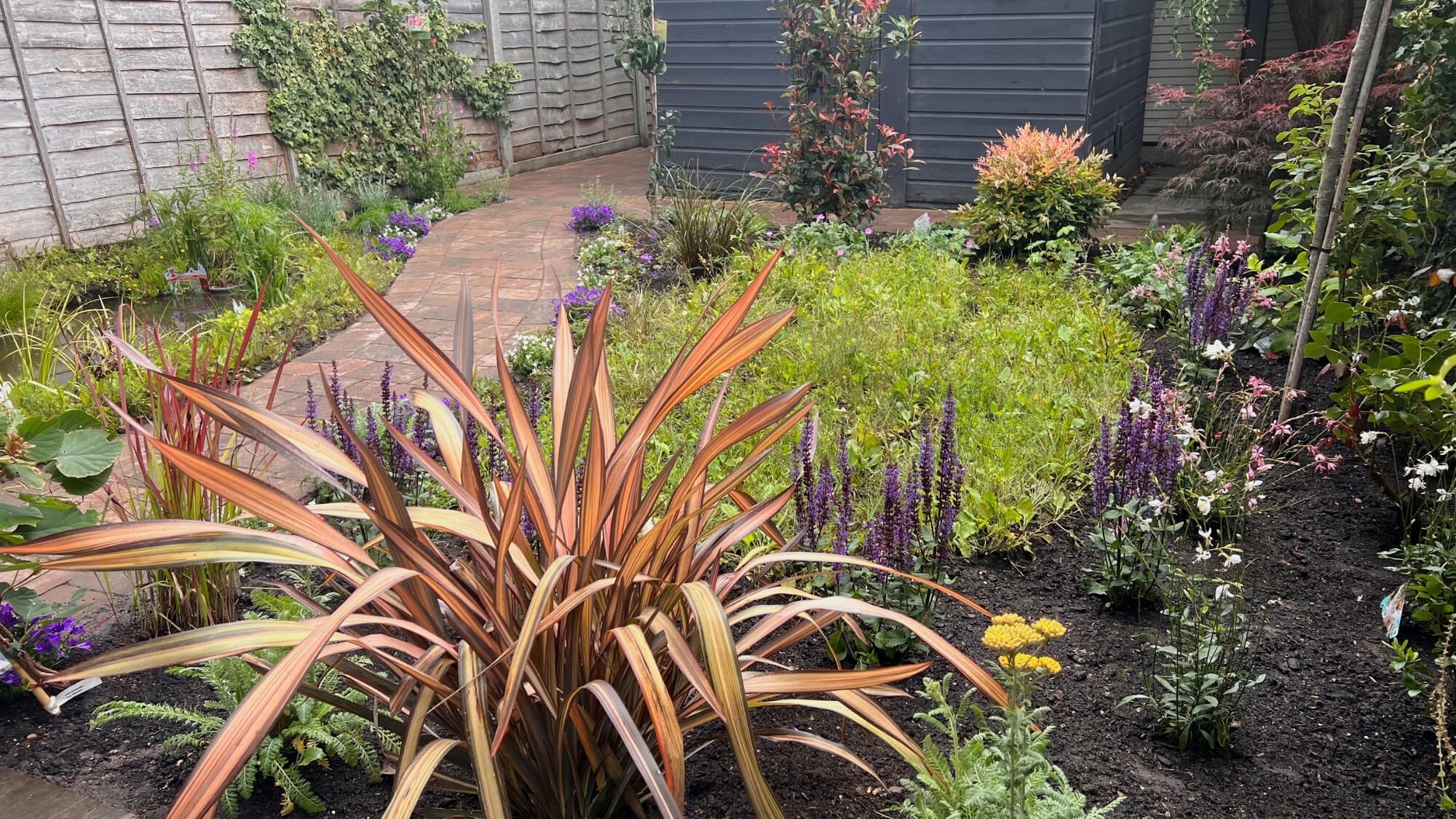 Small edible courtyard garden in Banstead with gravel paths, fruit trees, raised beds and container planting