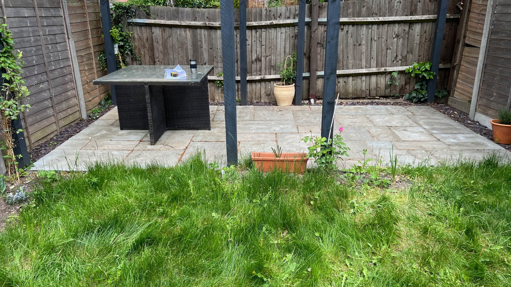 Overgrown lawn and unused patio area before garden transformation