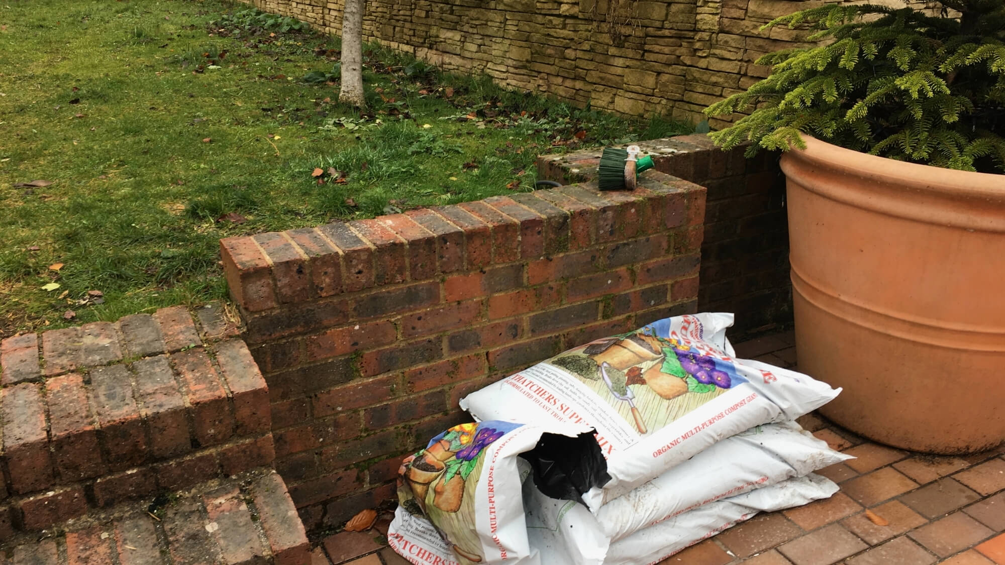 Before: dated brick retaining wall and cluttered corner in a South London garden before landscaping