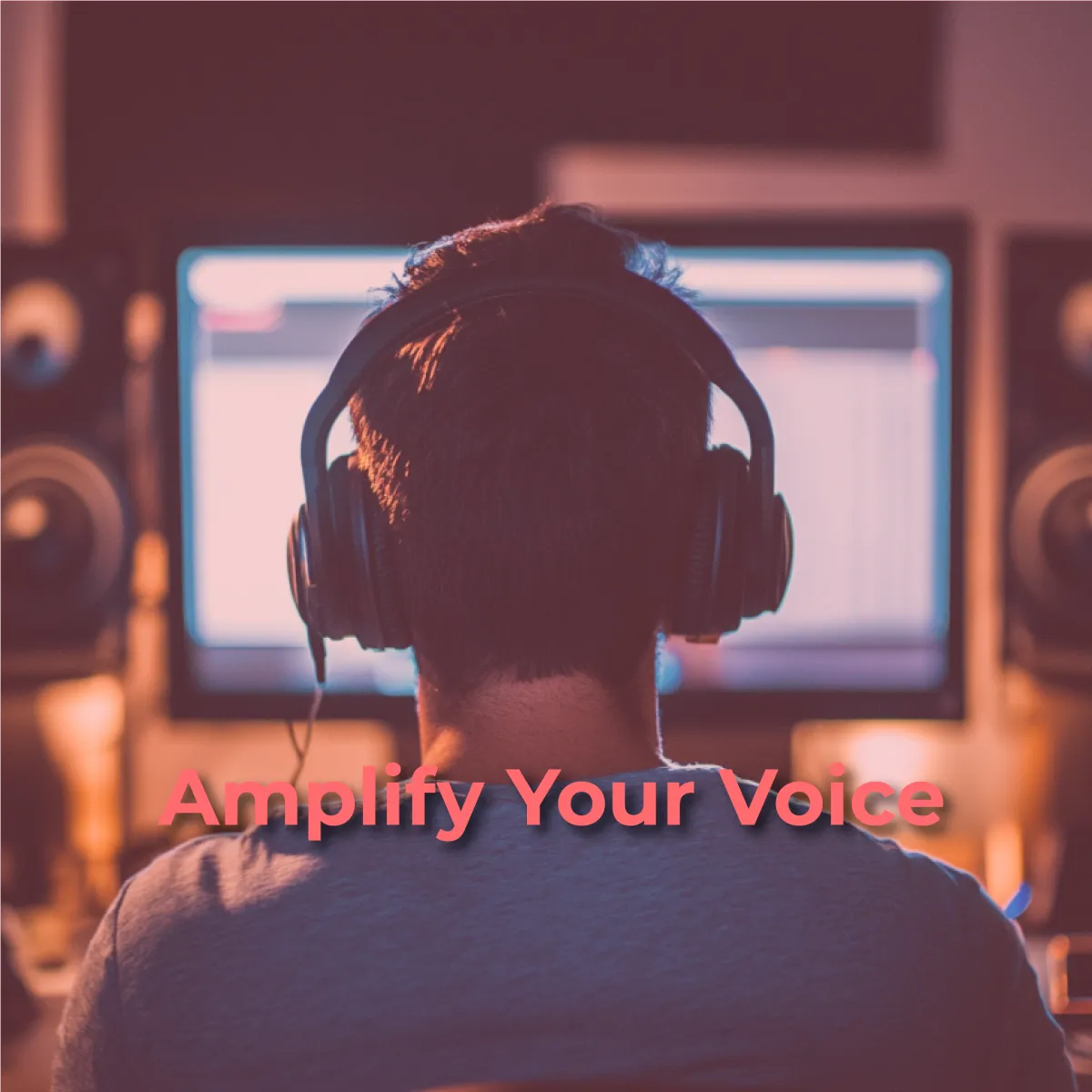 A person with their back to the viewer wears headphones and faces a computer screen, likely editing audio or video. The screen shows what appears to be a digital audio workstation or similar software with various tracks. The ambient lighting is warm, possibly indicating a studio or home office setting. Below the person, in a prominent pink font, are the words "Amplify Your Voice."