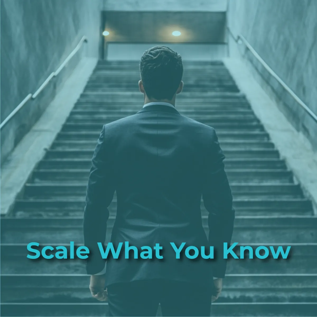 A silhouetted figure of a person in a suit is seen from behind, standing at the bottom of a long, concrete staircase that ascends into the distance. The staircase has metal handrails and is lit by unseen lights at the top, creating a sense of upward movement and ambition. The overall image has a cool, blue-green tint. The words "Scale What You Know" are superimposed in a bright blue color across the bottom of the image.