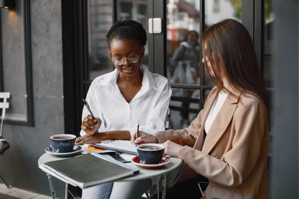Two professionals having a relaxed, authentic networking conversation in a coffee shop.