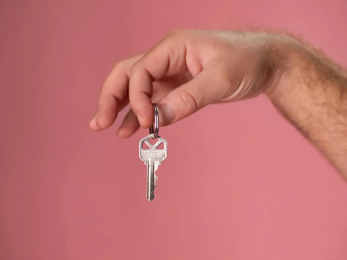 Person holding house key in front of pink background | Springfield 