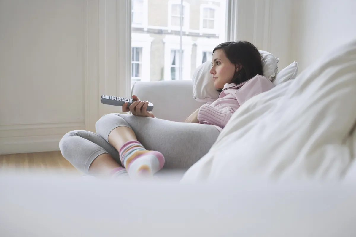 woman on couch holding remote