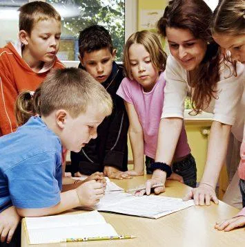 teacher looking at book with children around her