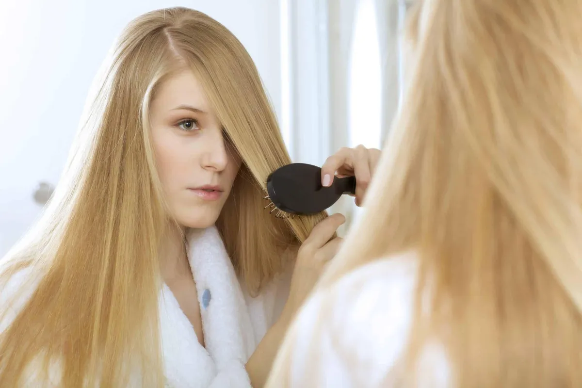 woman brushing hair in front of mirror