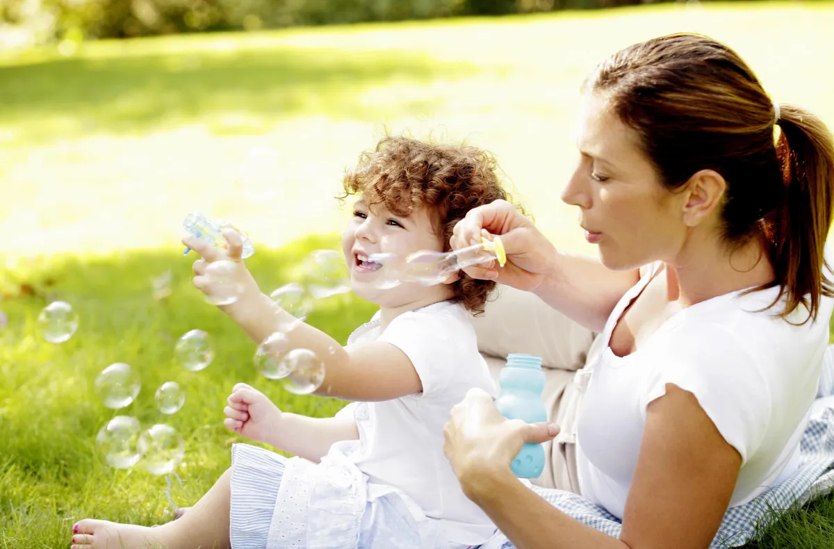 woman blowing bubbles with child
