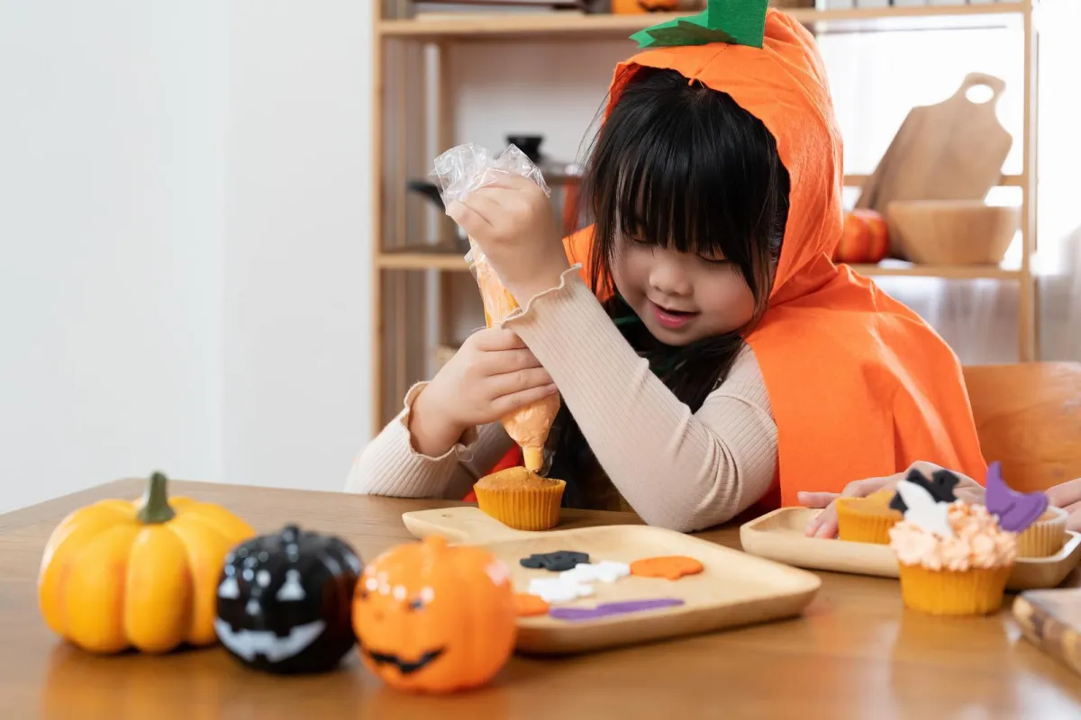 little girl making halloween cupcakes