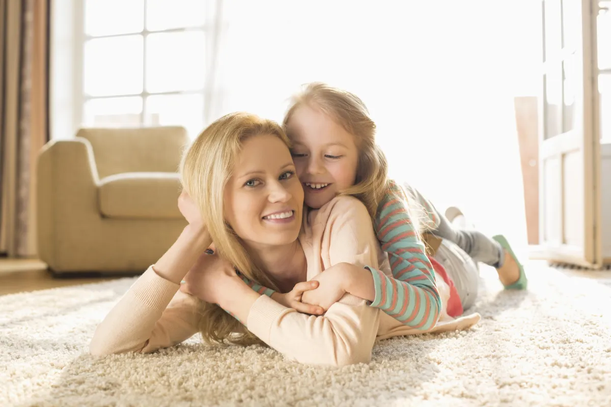 mom with daughter laying on her back laughing