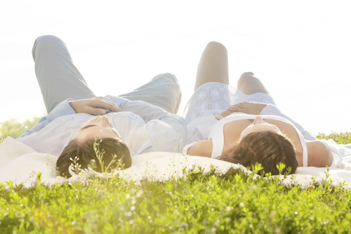 man and woman laying on the grass looking up at the sky