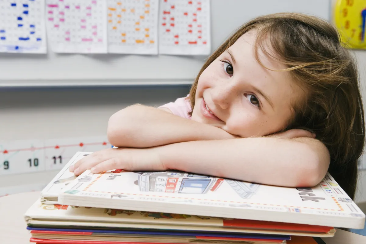 young girl laying head on school books