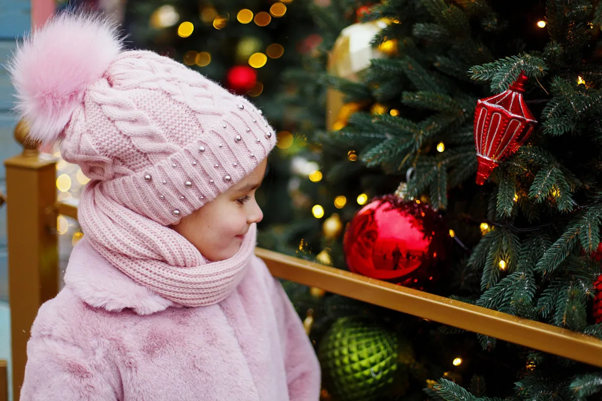 little girl looking at ornaments on a tree