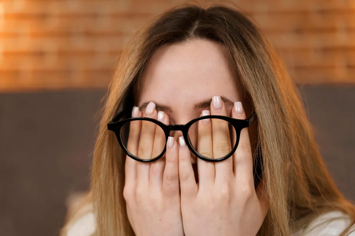 woman rubbing eyes under glasses