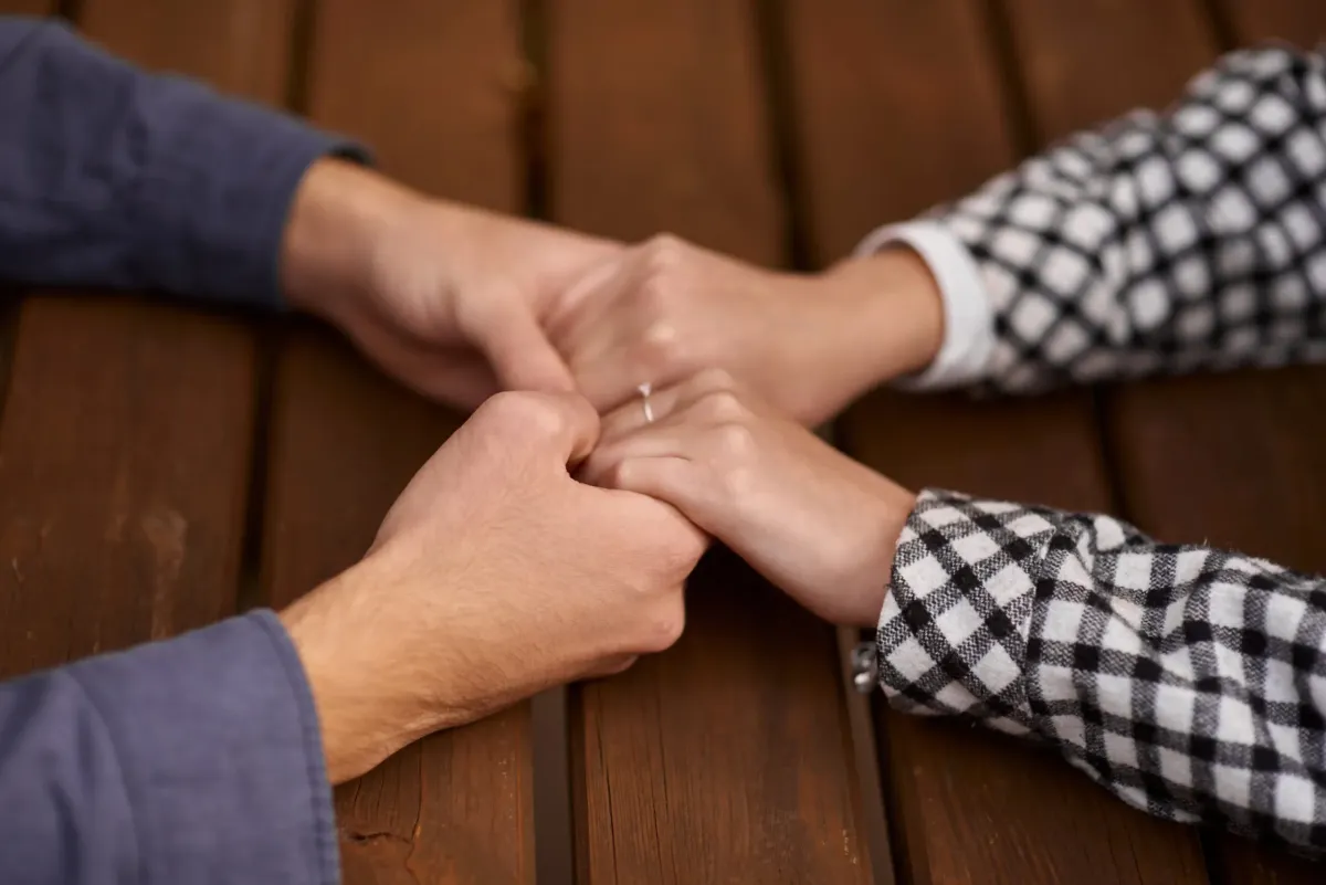 hands holding each other across table