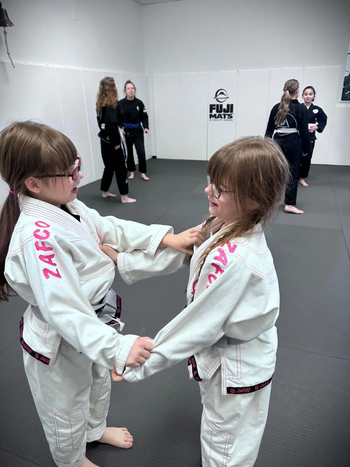 Two siblings practicing Brazilian Jiu-Jitsu together at Torrent BJJ martial arts class in Hanover MA