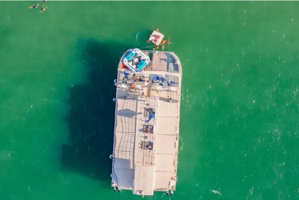 Vista aérea del Flamante Catamarán navegando hacia las Islas del Rosario con aguas cristalinas y arrecifes visibles desde la superficie.
