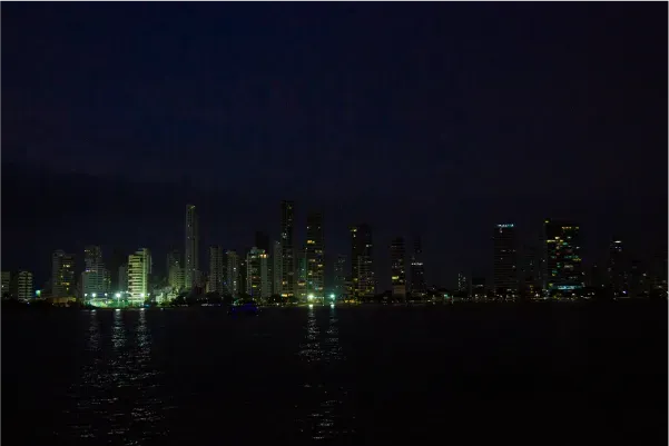 Vista panorámica nocturna de Cartagena desde el Flamante Catamarán con luces reflejadas sobre el mar.