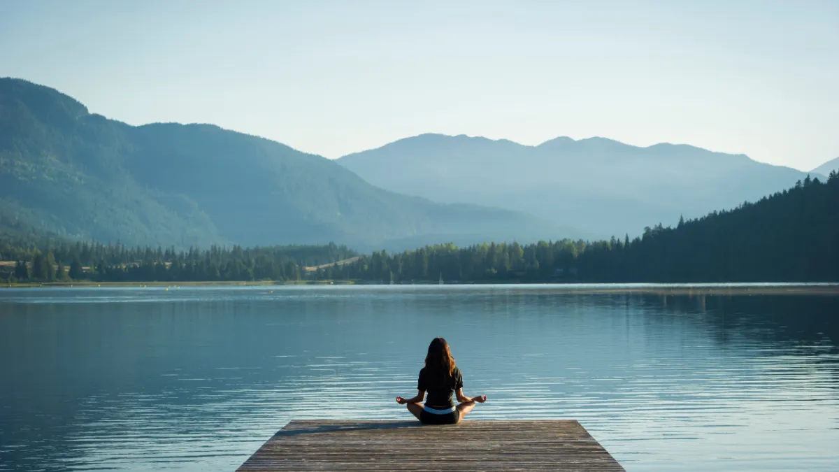 woman sat on pier of lake