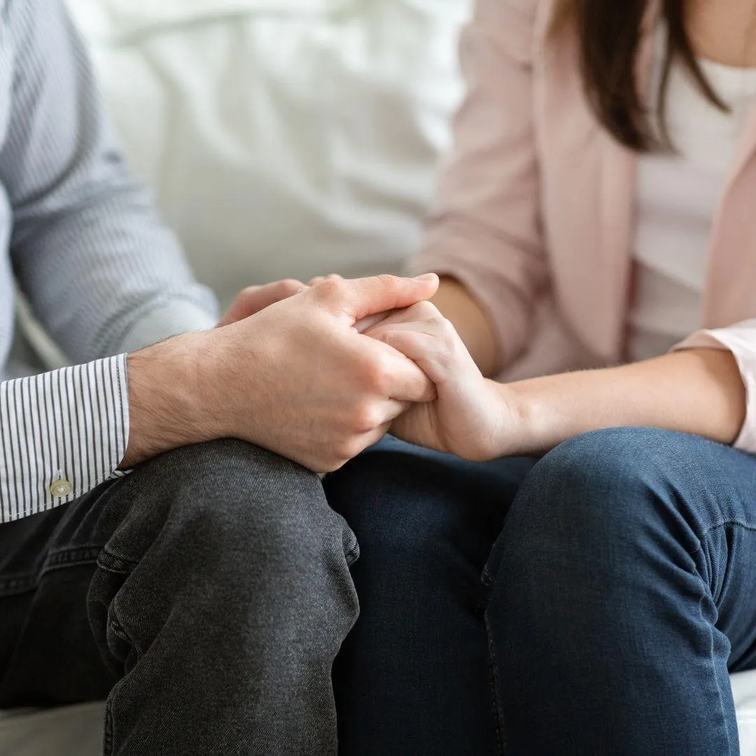 A couple sitting on opposite sides of the couch during a therapy session