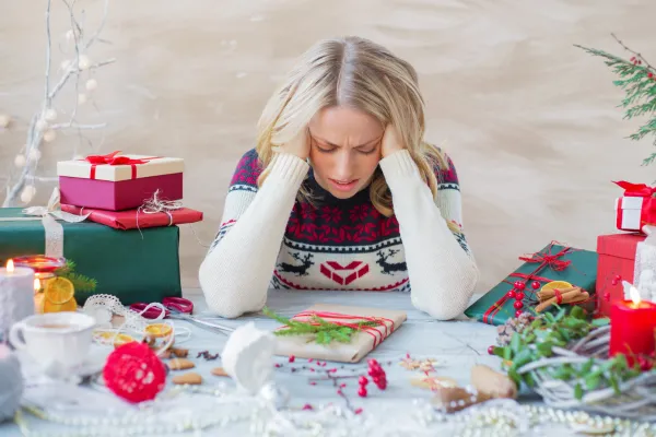 Overwhelmed mom juggling wrapping paper and gifts, showcasing the holiday stress faced by working mothers.