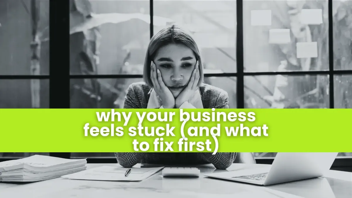 Frustrated businesswoman sitting at a desk with papers and a calculator, appearing overwhelmed by work.