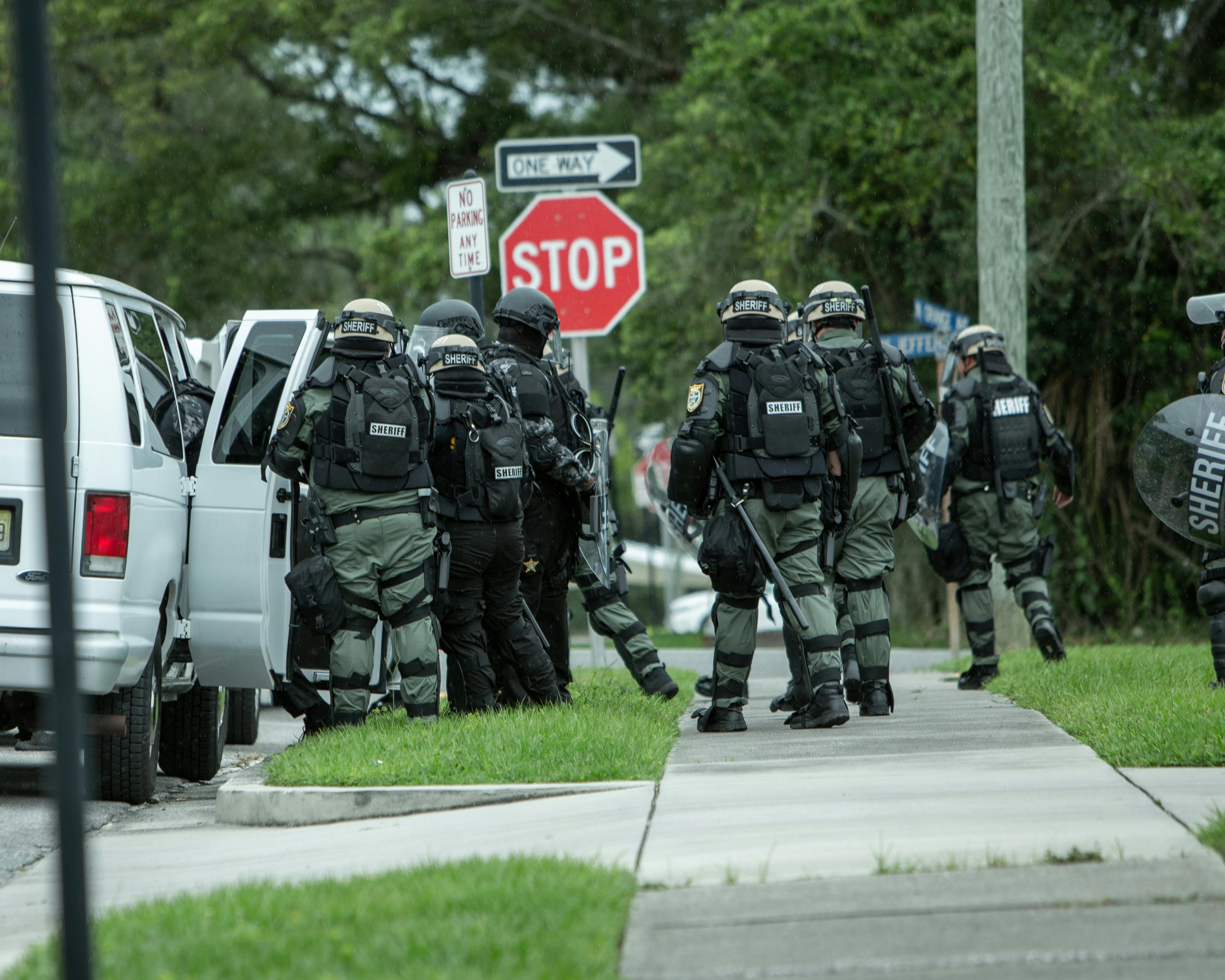 Law enforcement officers in tactical gear during a high-stress entry, illustrating the durability demands of police work