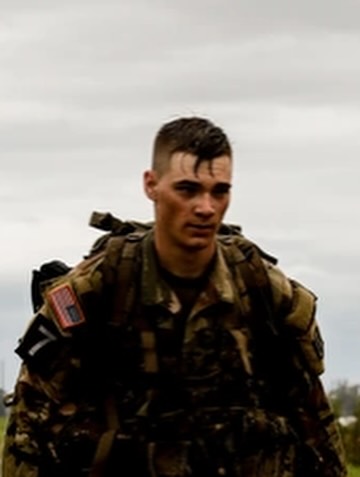 ROTC cadet in uniform walking on a college campus