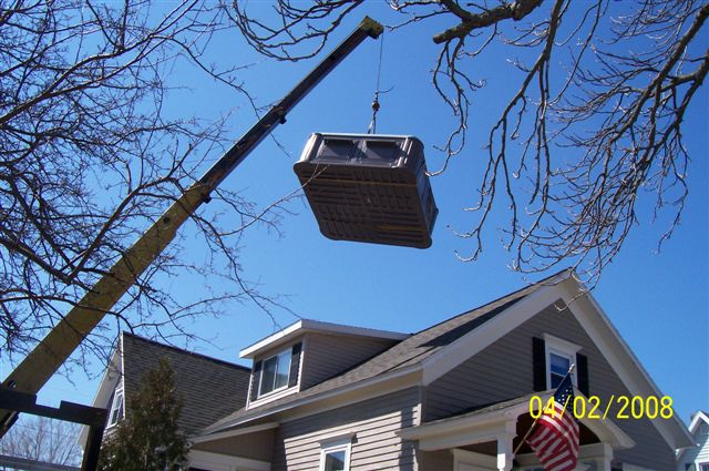 A crane lowering a spa over a customer's roof